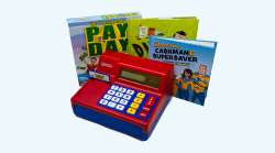 A toy cash register sits in front of three financial literacy books for kids.